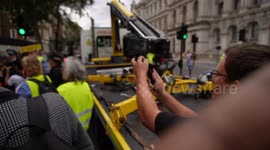 Protesters surround and protect Piers Corbyn's ULEZ mobile as a police tow truck arrives opposite 10 Downing Street to remove the vehicle, but the leave emtpy handed after being reminded by protesters that it would be illegal