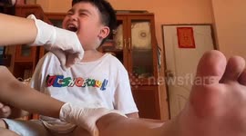 Little boy cries and giggles as mum treats his scraped knee