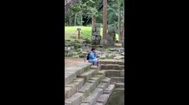 Monkeys climb on tourist at Angkor Thom temple in Cambodia