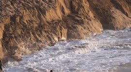 Daredevil youths ignore safety appeals from RNLI and scramble on the fast eroding danger sand cliffs at Crantock beach Cornwall