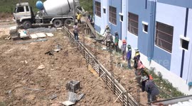 Team work Thai style on a small construction site, where workers from a line and manually move mixed concrete to where it is needed.