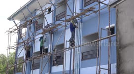 A team of Thai painters put the finishing touches to a new apartment building.