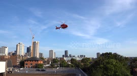 London Air Ambulance Taking Off from car parking in Croydon, London. Afternoon blue sky, skyscraper landmark.