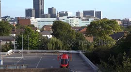 London Air Ambulance Taking Off from car parking in Croydon, London. Afternoon blue sky, skyscraper landmark.
