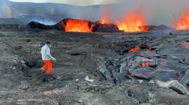 Scientist shovels molten lava into a bucket to carry it away for testing