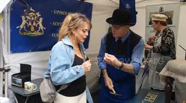 Danielle Nicholls attempts to upholster with a representative from The Worshipful Company of Upholders of the City of London at the Annual Sheep Drive and Livery Fair