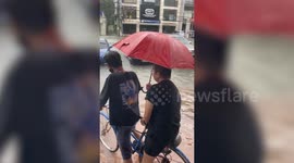 Biker struggles to pedal across deluge during storm