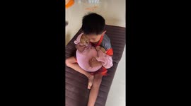 Toddler cradles tabby cat wrapped in blanket like a baby