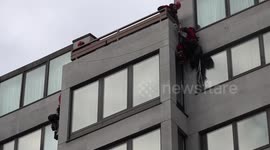 Greenpeace protesters unfurl banner as they abseil from London hotel, UK
