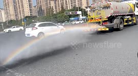 Rainbow forms behind water sprinkler truck in China