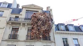 PILE OF CHAIRS HANGING ON A BUILDING? If you walk along the rue du Faubourg-Saint-Honoré in Paris and look up to the sky, you will undoubtedly see a stack of chairs hanging from the facade of a building, located just opposite the Bristol Hotel. But then w