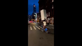 Man balances refrigerator on head while riding bicycle in Chicago