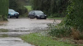 Vehicles drive through flooded road in Yapton, West Sussex, UK
