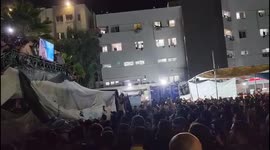 Crowd of displaced Gazans follow conflict on big screen outside Al-Shifa hospital