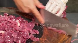 Uncooked joint of raw beef TWITCHES as butcher cuts meat
