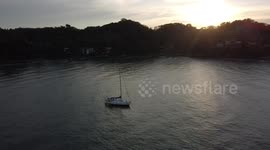 Drone video seeing a sailingyacht enjoying the Sunset in Sayulita Mexico, with mountains and beautiful beach