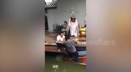 Clumsy tourist sinks boat while disembarking for restaurant beside canal in Thailand