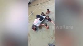 Mother and baby ferried on old fridge through floods in the Philippines