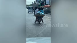 Kids cling onto both sides of mum's overloaded motorcycle in Phnom Penh, Cambodia