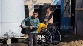 Palestinian boys try to fill water bottles for drinking in light of the continuing Israeli attack on the Gaza Strip