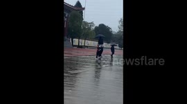 Three students using one umbrella in Huaihua, China