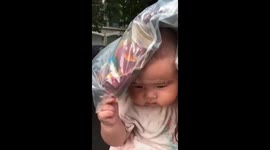 Toddler shields from the rain with package over her head