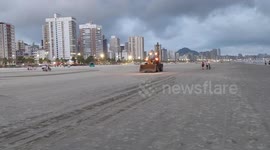 Tratores fazem limpeza na areia da praia na cidade de Praia Grande, Brasil