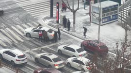 Pedestrians unite to help push vehicles struggling to ascend steep snowy road in China
