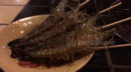 Live prawns wriggle on skewers at a Saigon restaurant
