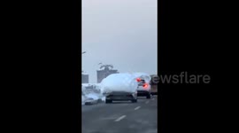 Car navigates road with thick rooftop blankets of snow in China