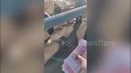 Good samaritans collect scattered money on road following crash