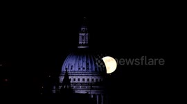 The first full moon of the year rises from behind St Paul's Cathedral in London