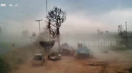 Workers shelter behind excavator as storm lashes field in Thailand