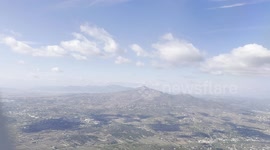 Flying over Greece on an airplane. The day is sunny and we can clearly see the land reliefs and the sea.