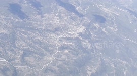 Land seen from an airplane flying over Eastern Europe. It's a place by the sea and there are many turbines to generate wind energy.