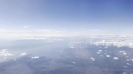 Traveling over Eastern Europe on an airplane in a sunny day. We can see clearly the land reliefs, some clouds and a blue sky.