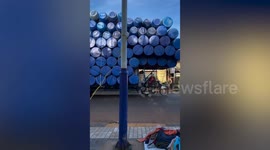 Motorcycle carrying HUNDREDS of oil drums crawls down road