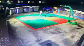 Two lads playing one-on-one basketball both slip over at the same time