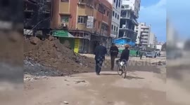 Palestinian films as they walk through streets of destruction in central Gaza