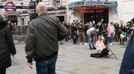 A St Patricks day fan celebrates listening to a busker in Picaddily Circus