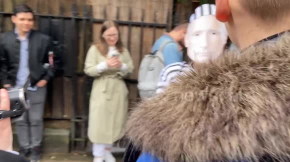 Protester dressed as Putin in prison clothing and wearing handcuffs walks past huge queue of Russians waiting to cast their vote at the Russian Embassy in London