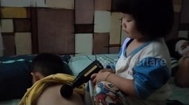 Adorable 3-year-old girl massaging her elder brother