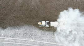 Remarkable aerial footage of a tractor spreading lime in a field