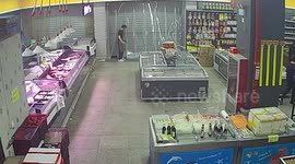 Employee struggles to close grocery store's shutters as powerful wind blows it open