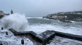 Powerful waves crash ashore as spectators observe the high tide, following a yellow wind warning