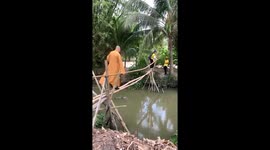 A monk falls into the ditch while crossing over a bamboo bridge
