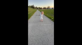 Toddler loves sunset strolls while walking with hands behind back just like her dad