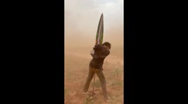 Farmer clings onto parasol while being battered by dust storm