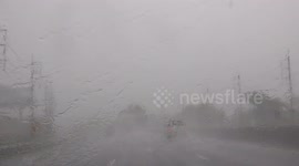 Driving on a highway in heavy rain with limited visibility in Thailand.
