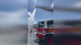 Fire truck helps schoolchildren to cool off by spraying them with water